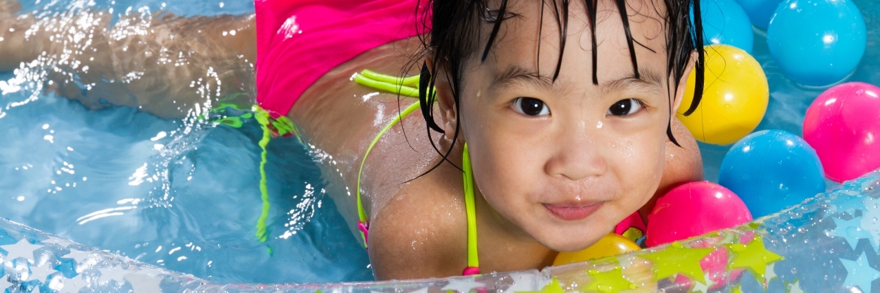 Fun Summer Activities for Kids With Cerebral Palsy Girl playing in kiddy pool.