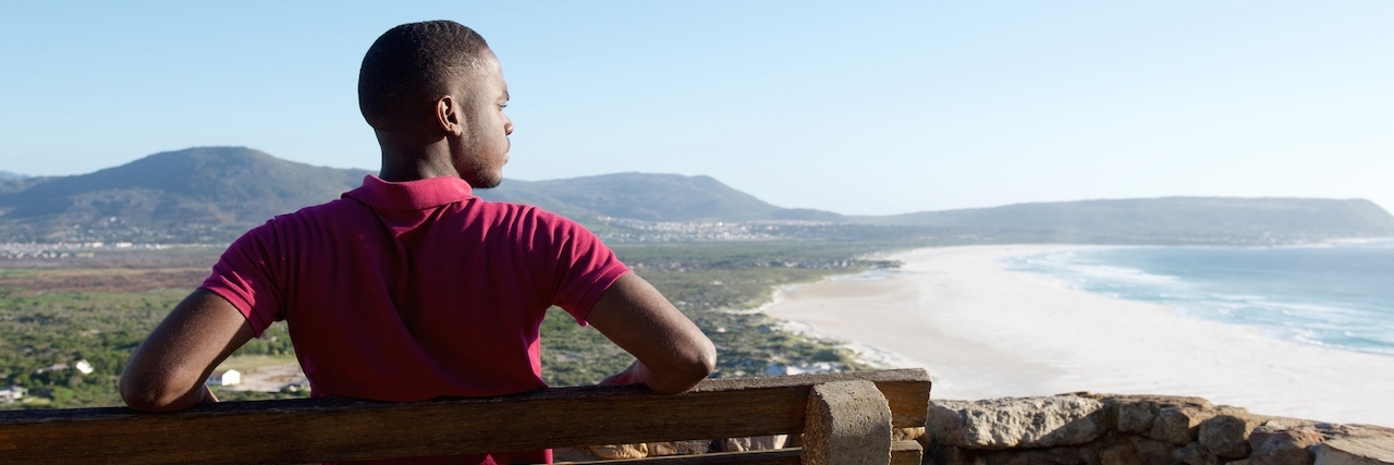 How to Cope With Illness Leading to Depression and Anxiety Rear view portrait of young man sitting relaxed on a bench and looking at the sea