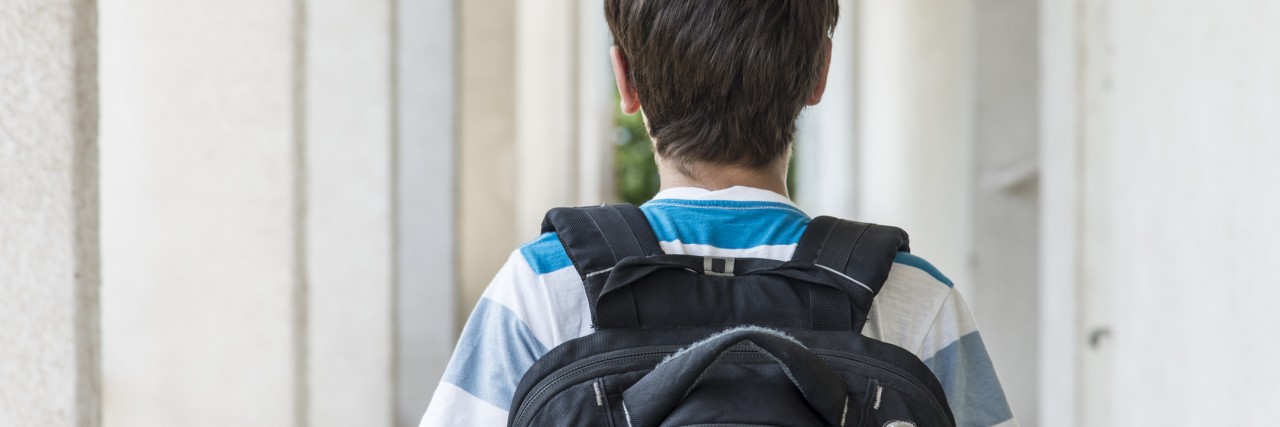Teenage school boy with a backpack walking to school