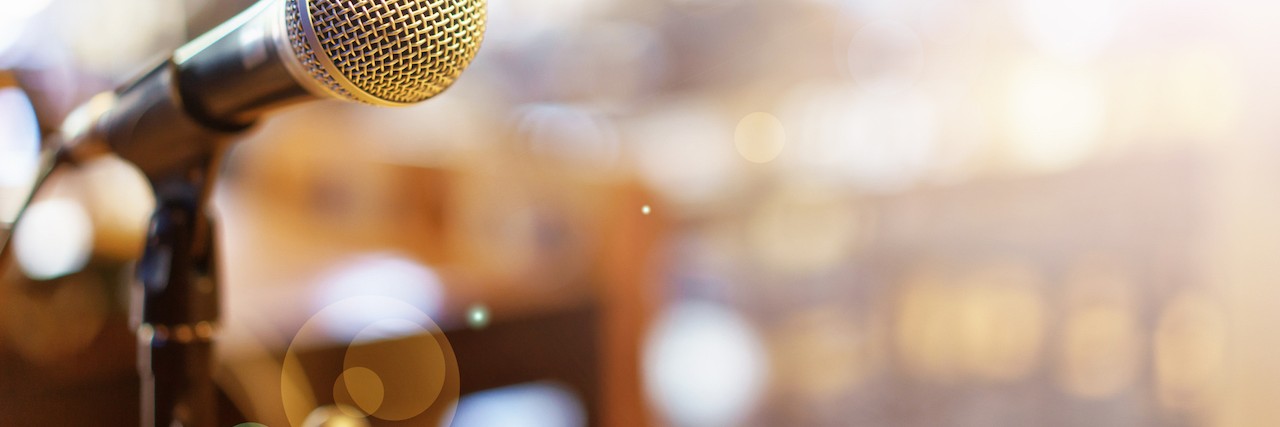 Microphone over a blurred photo of a conference hall