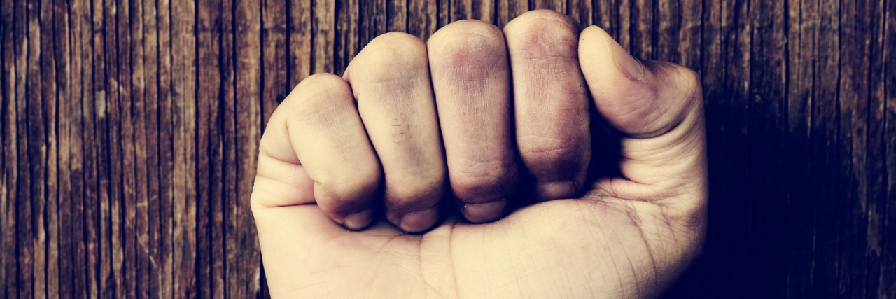 Dermatillomania: What People Who Pick Their Skin to Know hand in a fist with a rainbow wrist band