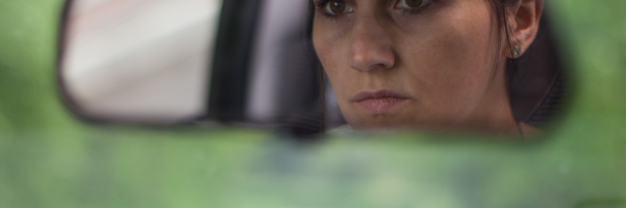 young woman reflection in rear view mirror