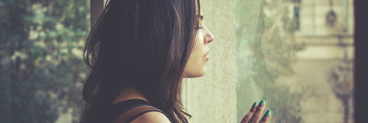 Why It's Hard Being Young With a Chronic Illness woman looking through window
