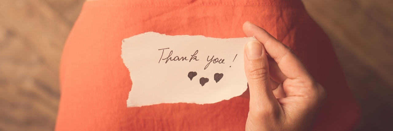 Positives of Living With Anxiety Top view of a woman with pink dress holding a thank you note in her hand