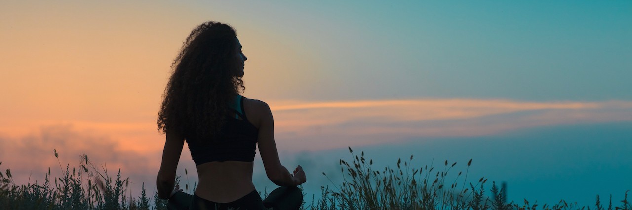 Learning to Accept Chronic Pain Condition Without Giving Up Silhouette of young woman sitting on grass at sunset