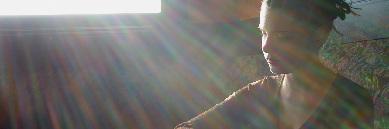 woman sitting along with light shining through a window