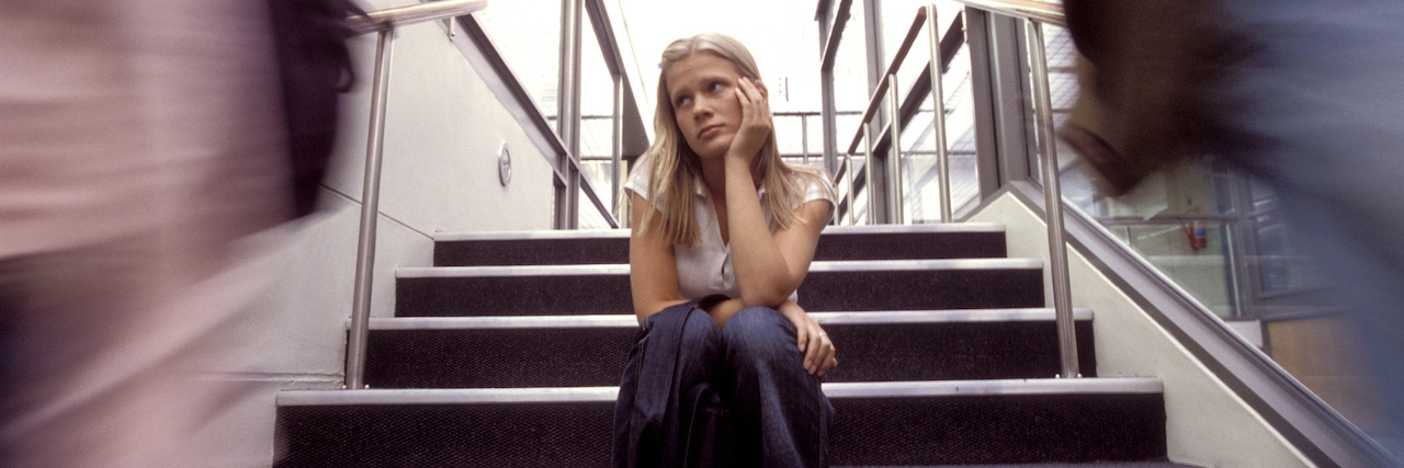 Self-Harm Scars Aren't Something to Joke About student sitting in a stairwell of a school