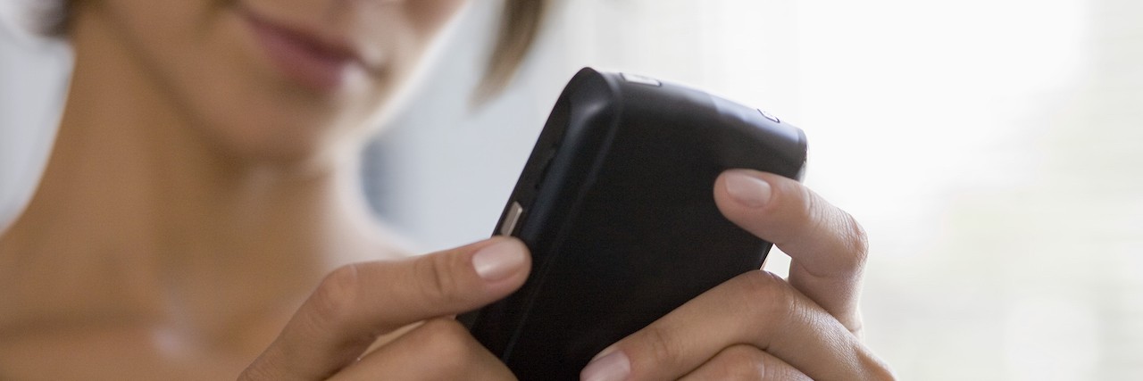 Asking for Help When You Have a Chronic Illness Woman holding phone, looking down at it