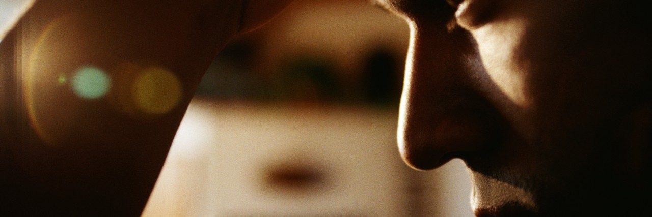 A Letter to Someone Struggling With Chronic Pain Man looking down with his hand on his head