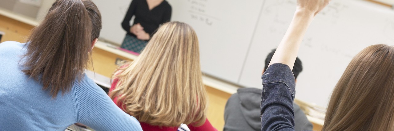 teacher at front of classroom and student raising her hand