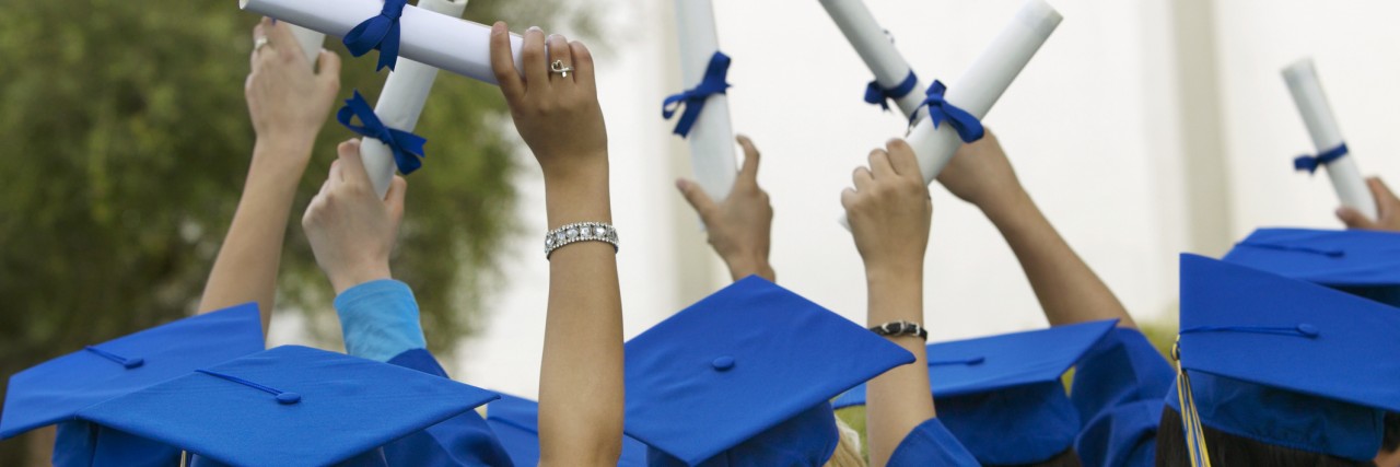graduates holding diplomas in the air