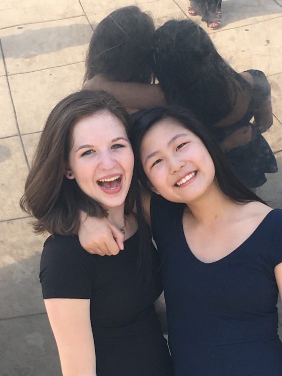 two teenage girls wearing black shirts with arms around each other