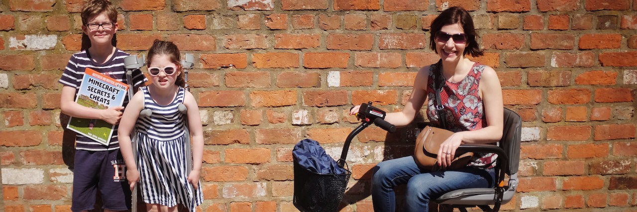 Letter to Kids From Mom With Multiple Sclerosis woman sitting on scooter next to two young kids