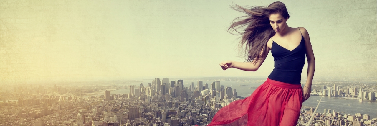 Woman walking on a balance beam over a cityscape