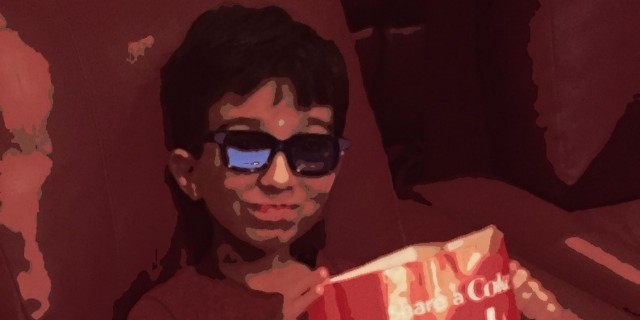 little boy with popcorn in lap at the movies