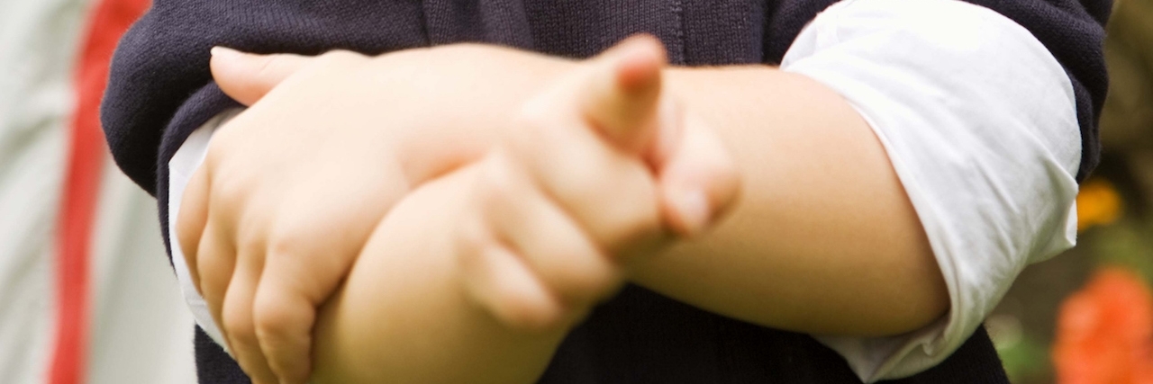 boy with arm crossed and pointing finger straight ahead