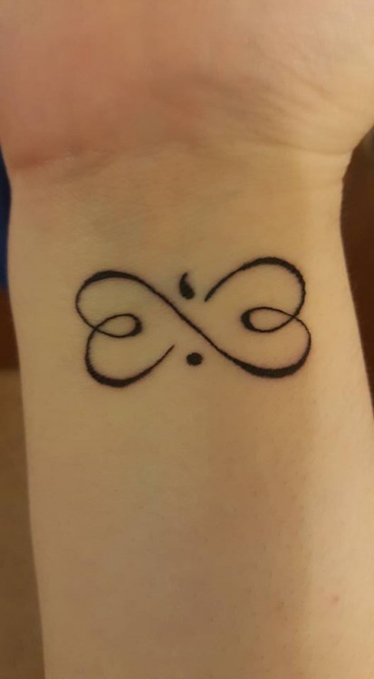 tattoo on wrist of an infinity sign with a semicolon in the middle