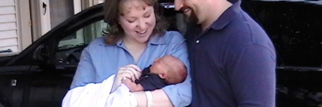 The author holding her baby with her husband standing next to them