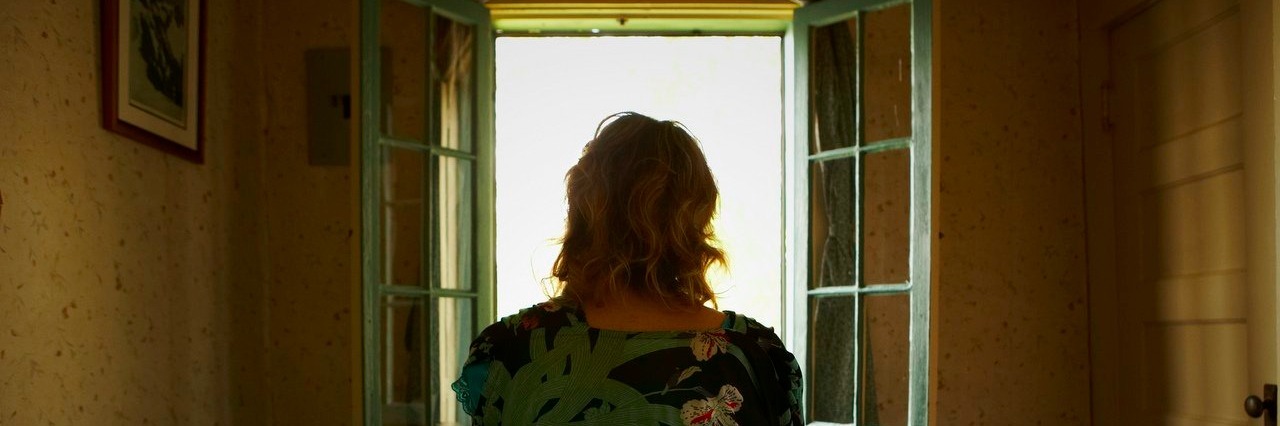 Woman sitting on bed looking out window