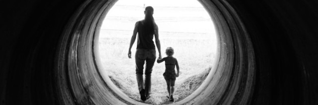 A black and white photo of a woman and child walking from behind