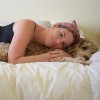woman laying on a bed cuddling with a dog