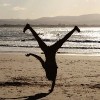 Person doing a cartwheel on the beach with the sun setting in the background