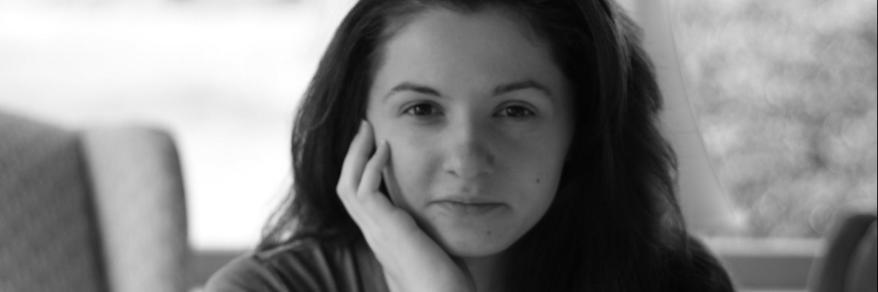What the Reality of Depression Looks Like Woman seated and facing camera in front of window seal