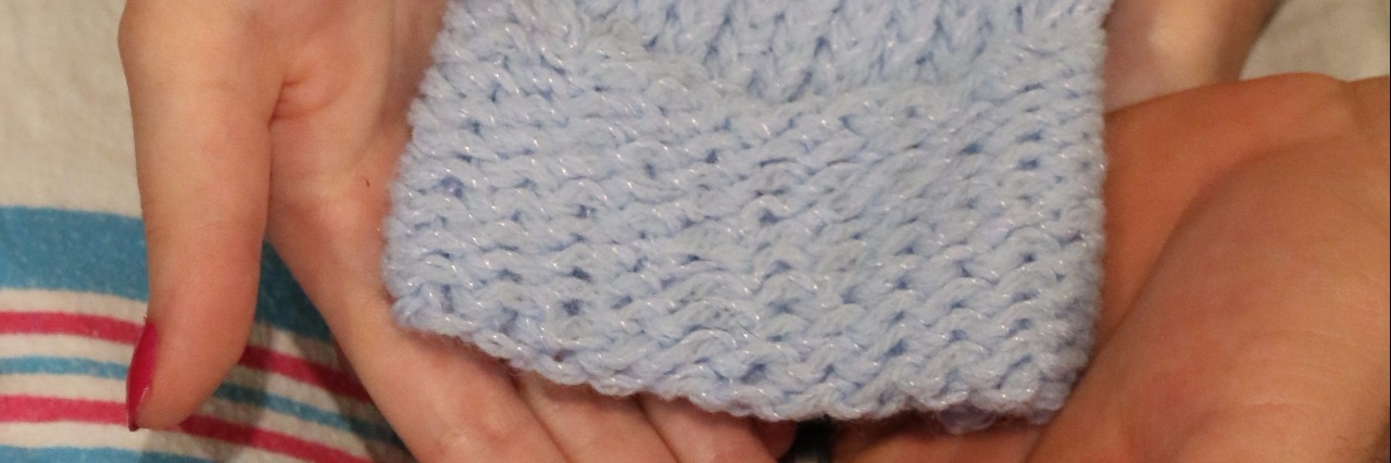 How a Nurse Helped Me Through the Premature Birth and Death of My Son three sets of hands hold a tiny blue knit hat