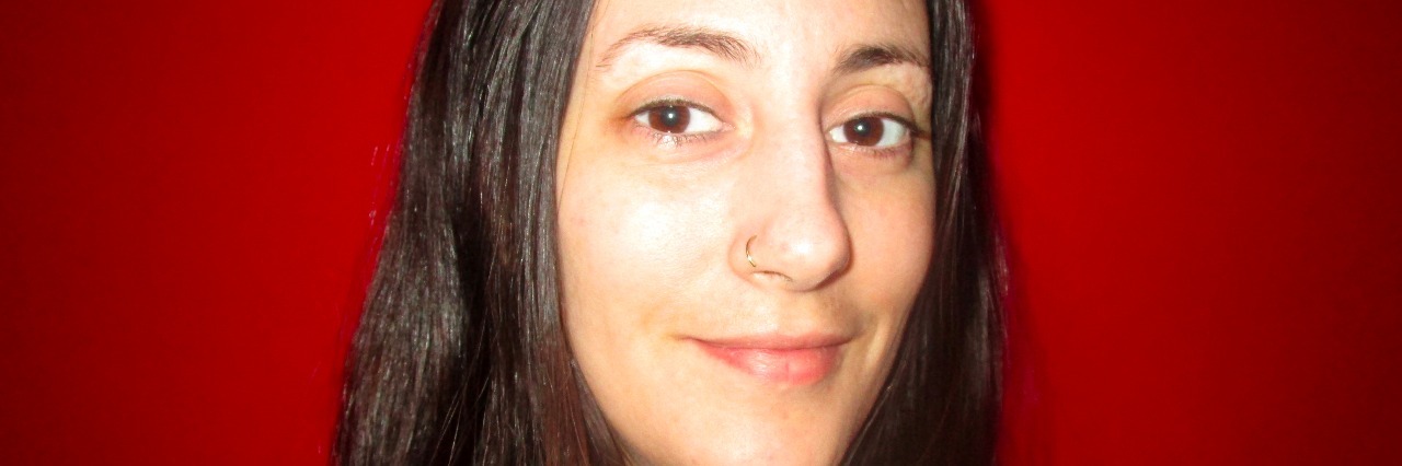How Dermatillomania Affected My Life Woman in front of red wall