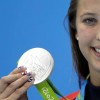 Kathleen Baker holding up her silver Olympic medal for the camera