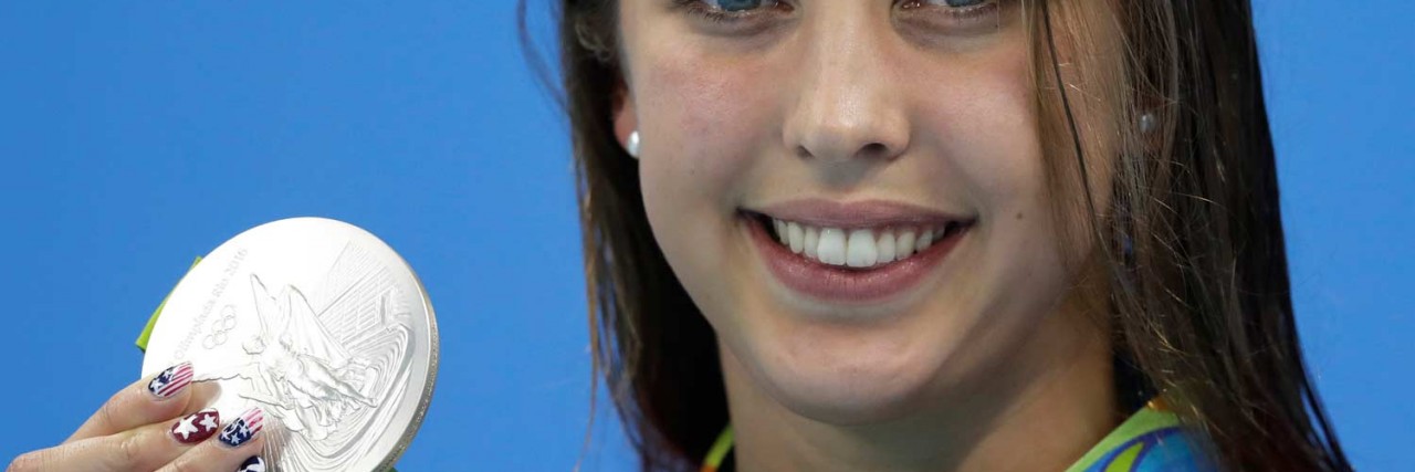 Response to Kathleen Baker Winning Medal By Woman With Crohn's Disease Kathleen Baker holding up her silver Olympic medal for the camera
