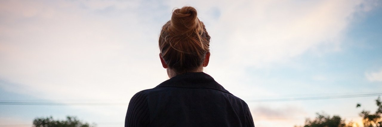 Why I Choose to Write About My Chronic Illness young woman looking at the sunset