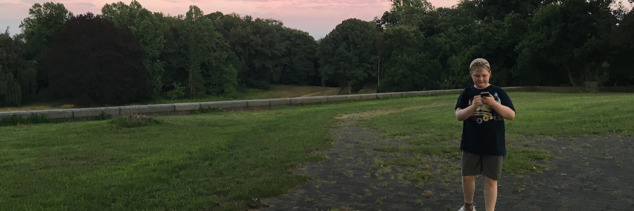 How Pokemon Go Gave Me My Son Back A young boy plaing Pokemon Go on his phone in a park
