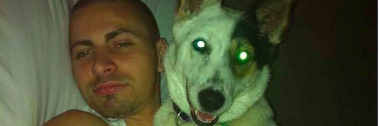 Why I Speak About Suicide After My Son's Death A young man holding his dog while lying on his bed.