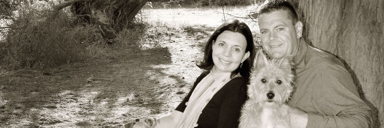 husband, wife and two dogs sitting under tree