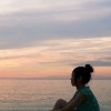woman sitting looking and sunset over ocean