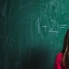 female student answering a math question on a chalk board