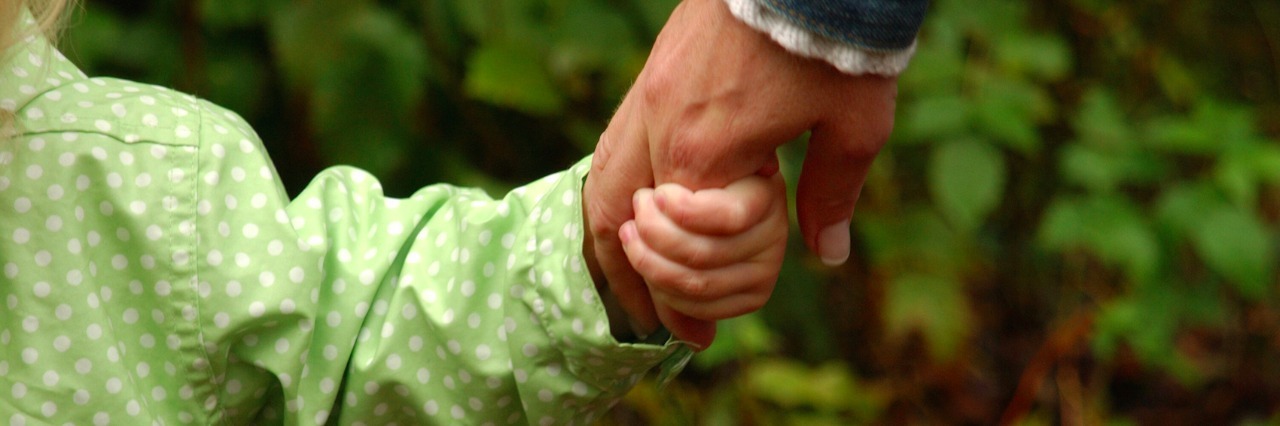 Parent holding child's hand in park