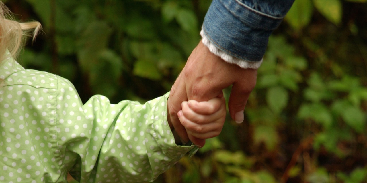 Parent holding the hand of a child with autism