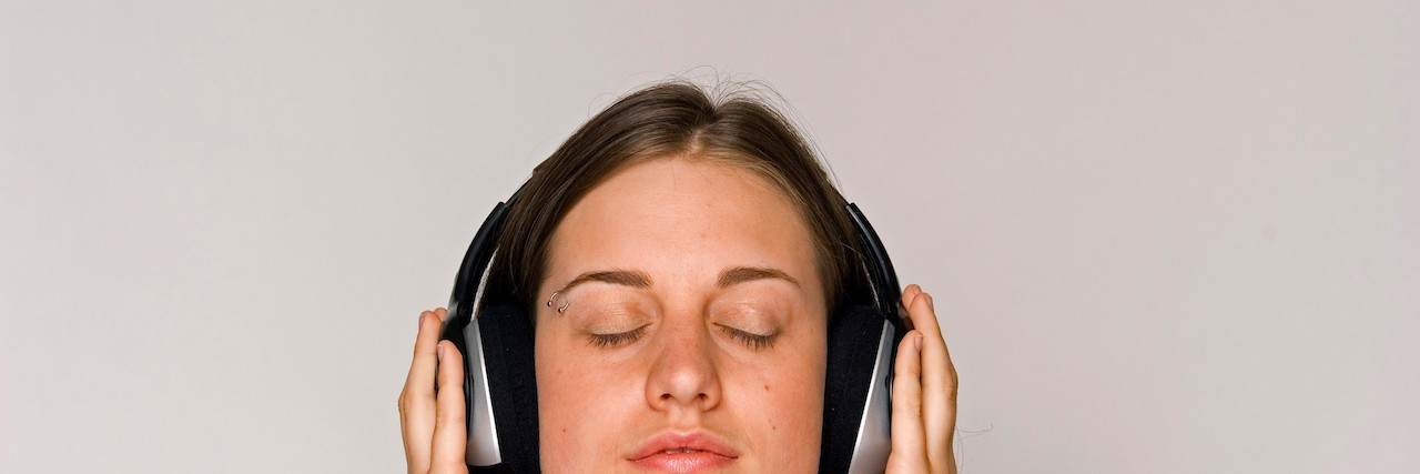 Young woman listening to music on headphones.