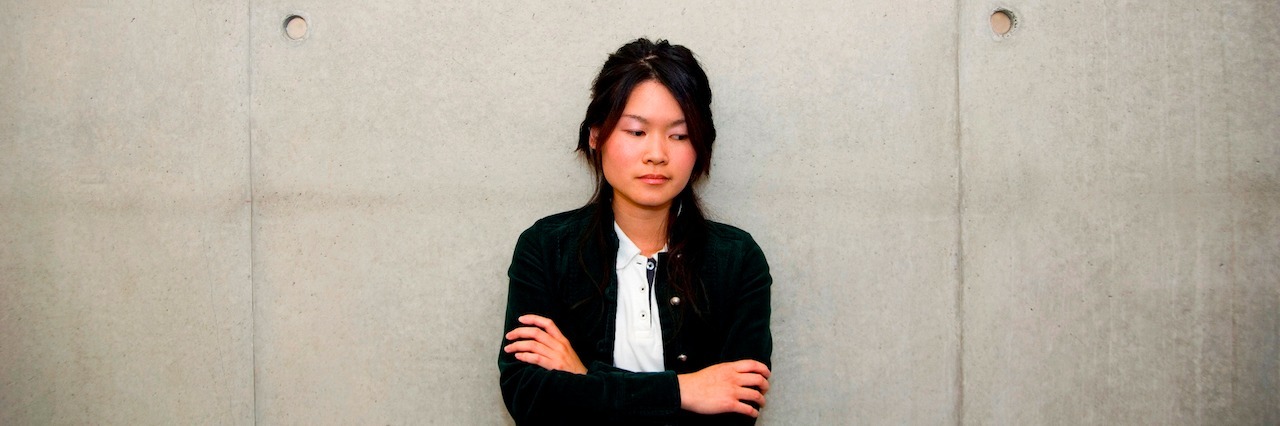 To Students With Social Anxiety on Your First Day of School A woman with her arms crossed, looking to the side while leaning against a cement wall
