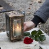 Woman lighting a candle next to a rose