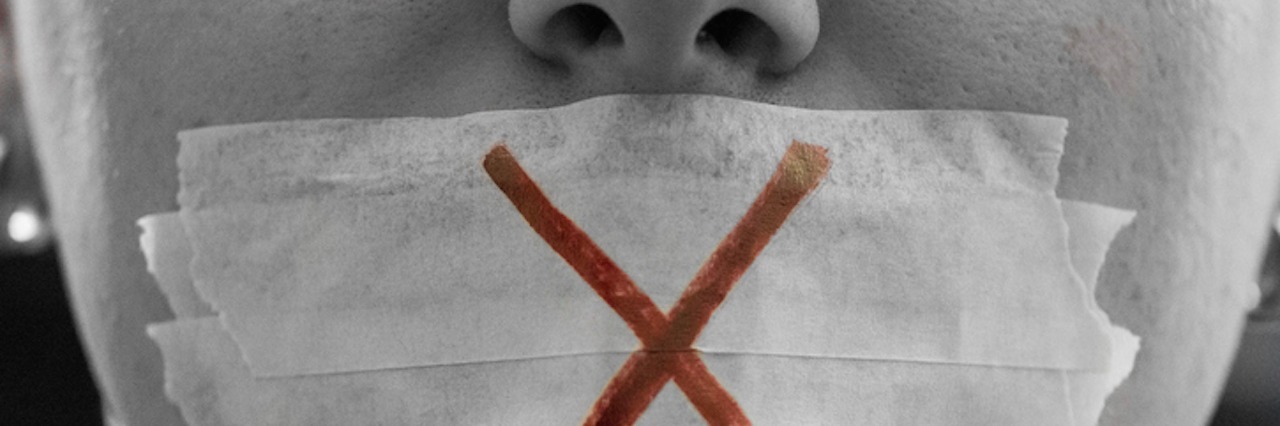 When Depression Makes it Hard to Write A male face with a taped mouth and a red cross on it.
