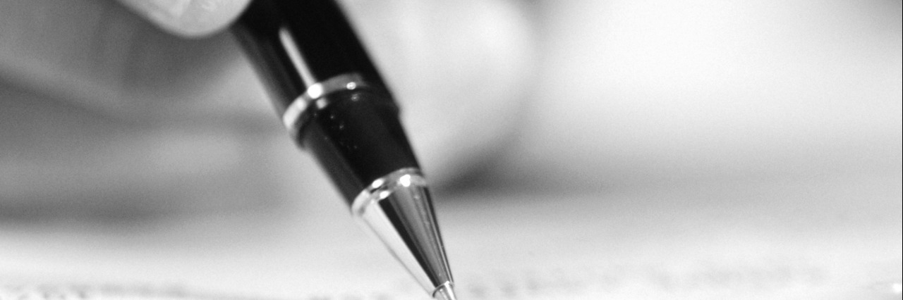 My Apology Letter to My Body: Where Our Healing Can Begin Black and white photo of person holding a pen