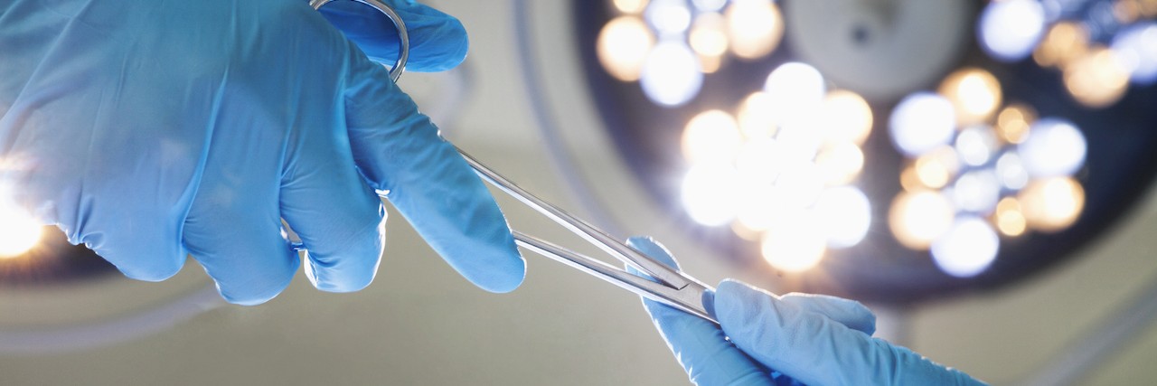 Close-up of gloved hands passing the surgical scissors