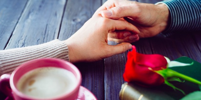 Romantic lovers dating. Male and female hands caressing with love. Couple on secret dating at coffee shop.