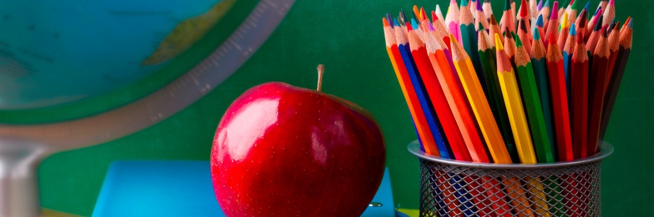 A Letter to School Principals About Spreading Autism Awareness Stack of books, red apple, globe and pencils