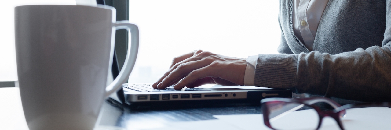 Advice for Managing Anxiety in College woman using laptop with coffee cup and glasses in foreground