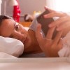 Woman Lying In Bed Checking Messages On Mobile Phone