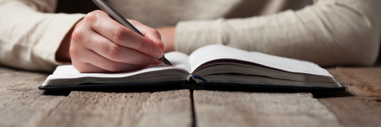 Letter to the Parents of a Child With an Eating Disorder hand writes with a pen in a notebook